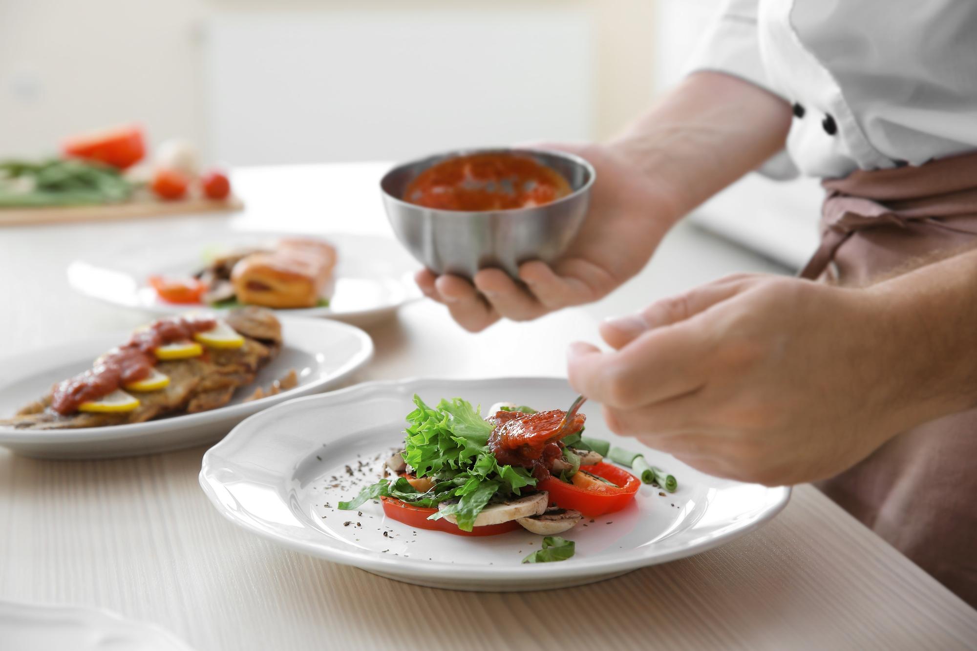 Chef arranging plated seasonal dish on wooden table